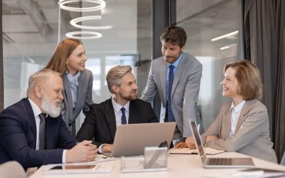 Business people discussing work together using a tablet and laptop taking notes in a modern office.