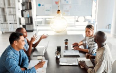 Bright lightbulb hanging from the roof while a group of businesspeople are having a meeting in an office at work. Bulb represents ideas, idea, creativity and inspiration. Colleagues planning together